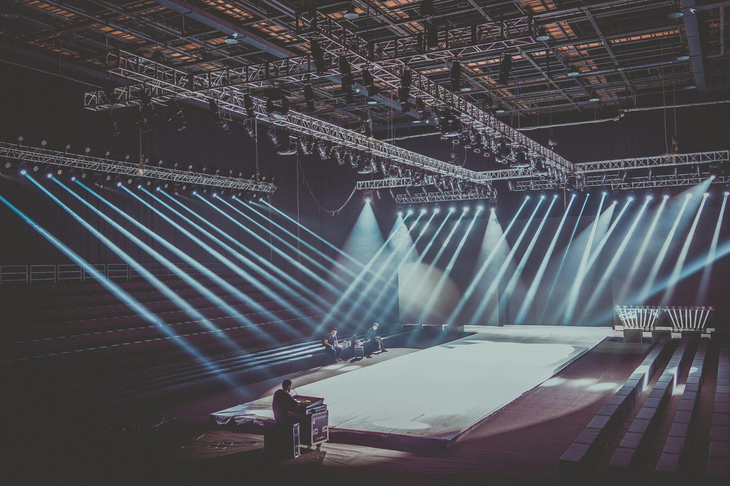 Empty event hall with stage lights illuminating a runway setup.