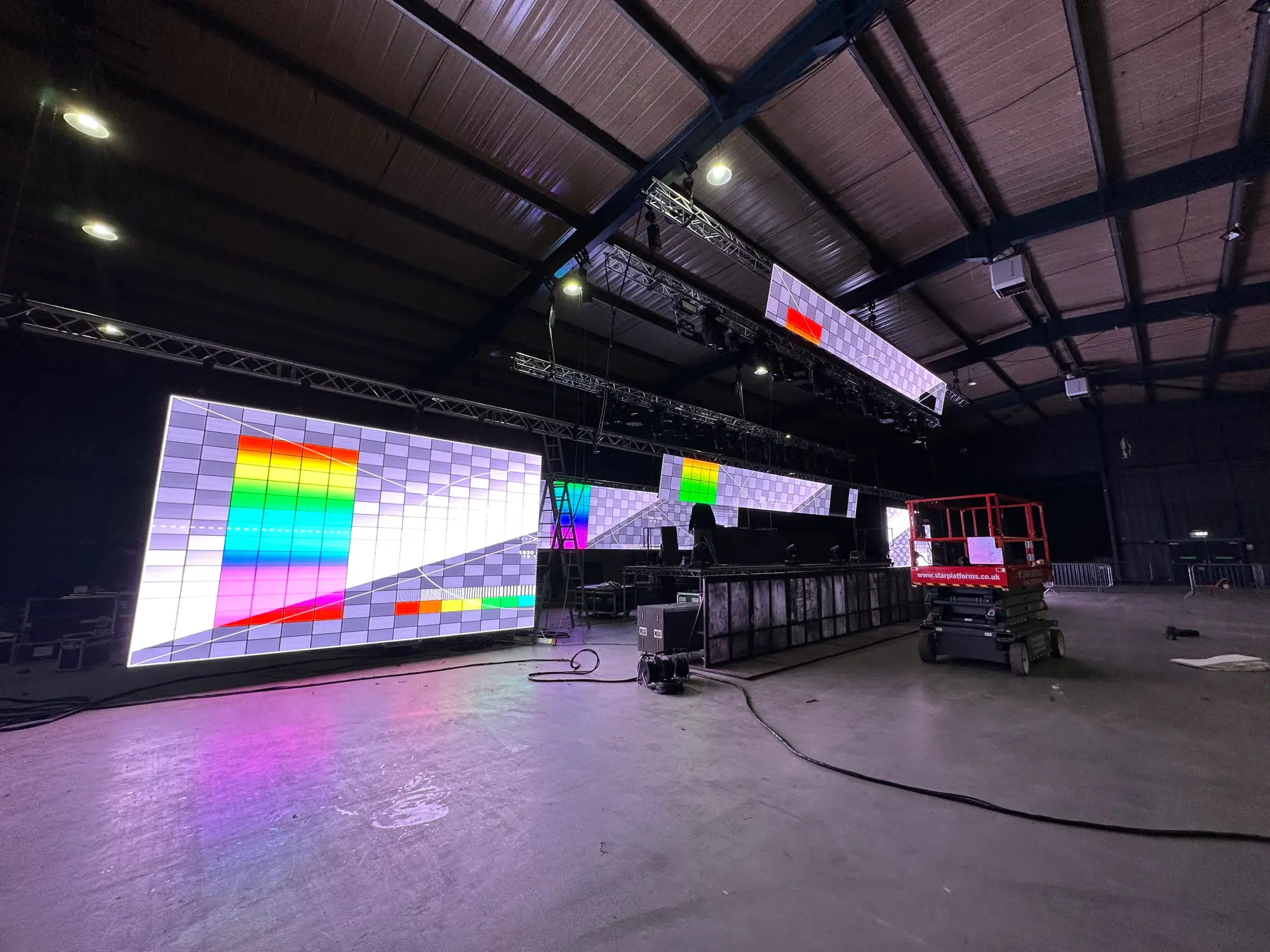 Indoor stage setup with LED panels showing colorful test patterns.