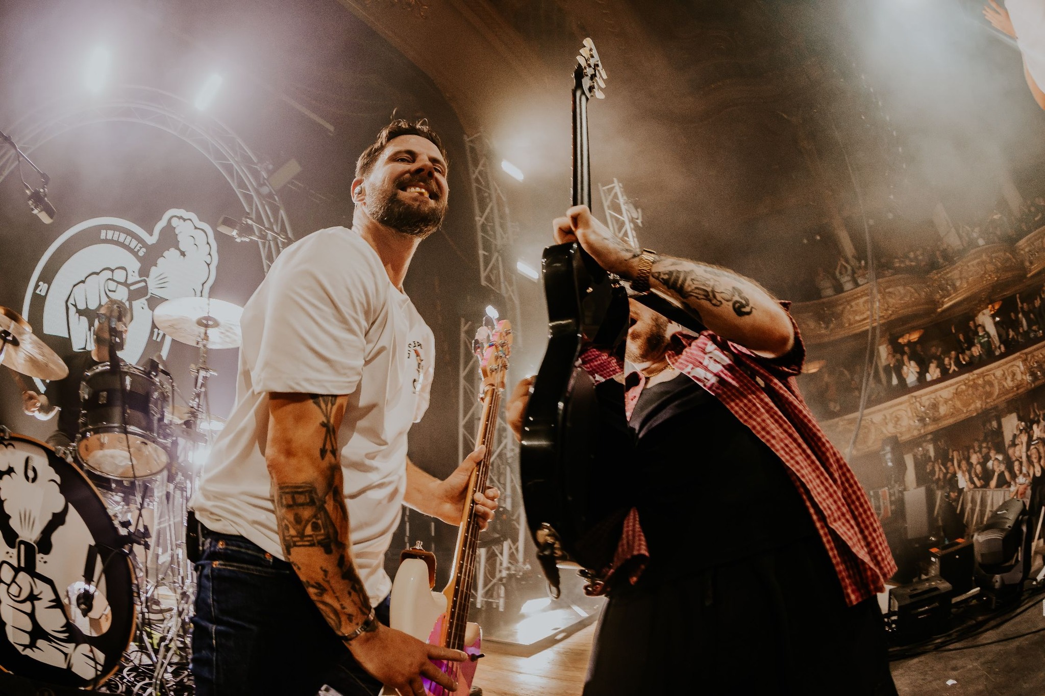 Close-up of musicians playing guitars on stage with cheering audience.